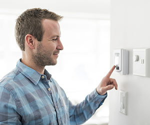 man saving energy by turning down the thermostat