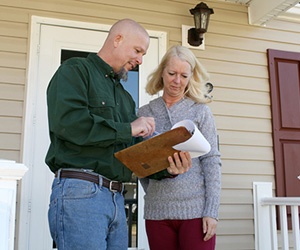 Contractor reviewing paperwork on a clipboard with a homeowner.