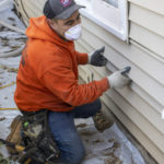 Worker removing exterior home siding.