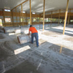 Workers arranging rolls of insulation in a large commercial space.