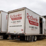 Two Rockweiler Insulation company trucks parked outside of a home.