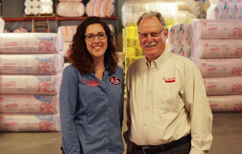 Two Rockweiler Insulation employees standing in front of insulation product in the warehouse.