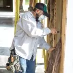 Worker installing wall insulation.