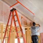Worker preparing an interior wall for insulation.