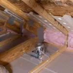 Batt insulation along the floor edge in an attic.
