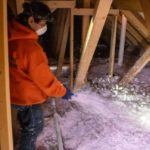 Worker spraying insulation in an attic