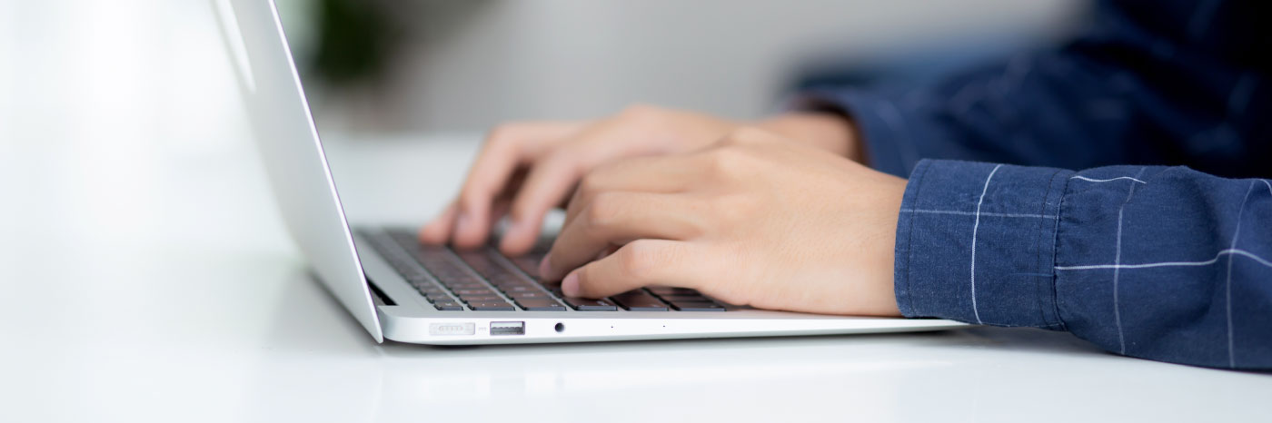 Closeup of a person's hands typing on a laptop.