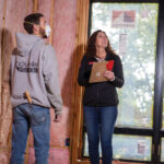 Two insulation workers examining interior insulation.