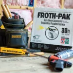 Insulation tools and equipment on the floor in front of an insulated wall.