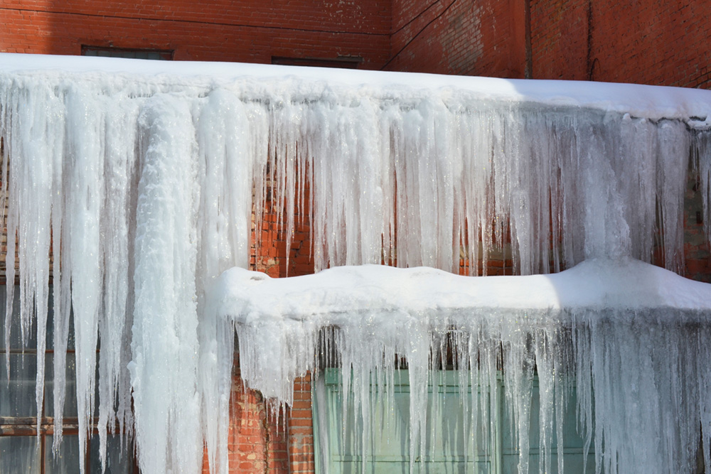 Long, dangerous icicles on a brick house roof.