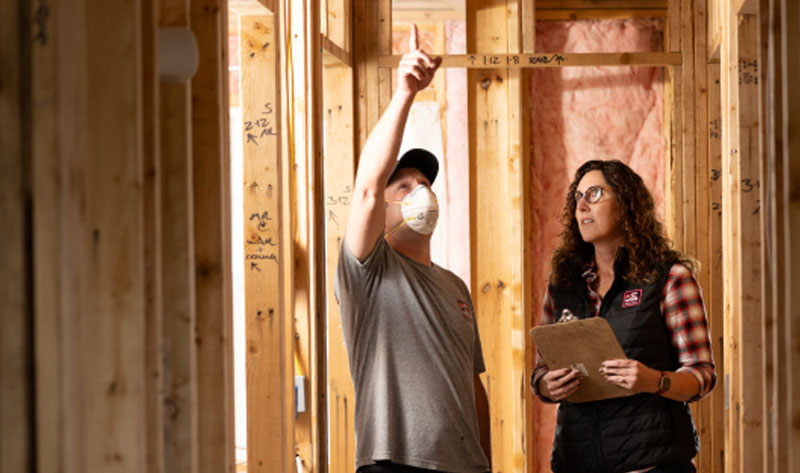 Renee Wilson, CEO of Rockweiler Insulation, reviewing framing work with a team member on a residential job site.