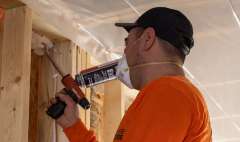 Rockweiler Insulation technician applying spray foam insulation to wall framing during residential construction.