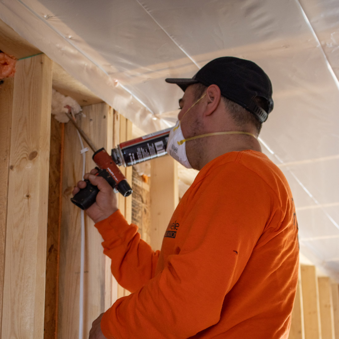 Rockweiler technician sealing wooden wall joints with spray foam