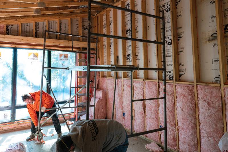 Rockweiler Insulation worker placing a large pink batt into a framed wall cavity.